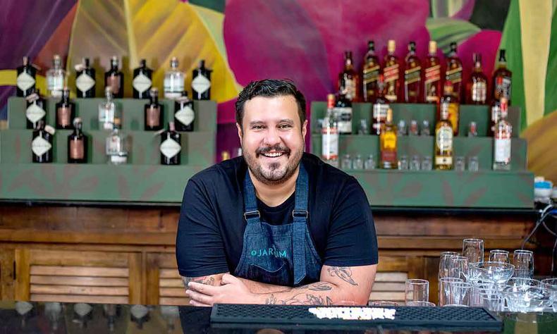 Caio Soter defende a importância da sustentabilidade na cozinha e de aproveitar o alimento até o final, sem desperdício(foto: Brejo/divulgação) Chef Caio Soter sorri, com as mãos na bancada, tendo ao fundo o bar com garrafas do restaurante Pacato