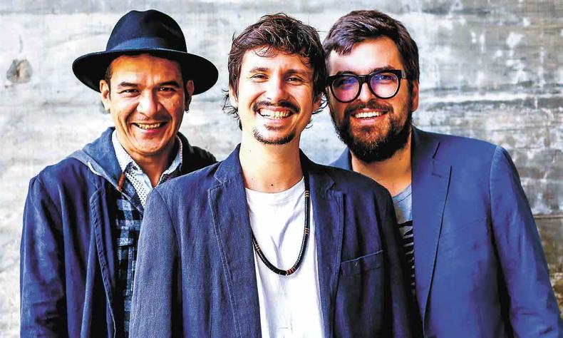 Os integrantes do Antonio Guerra Trio, de p, vestindo palets azuis sorriem para a foto