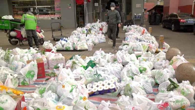 Pilhas de sacolas de mantimentos so colocadas no cho do lado de fora de um mercado de Pequim aguardando entregadores