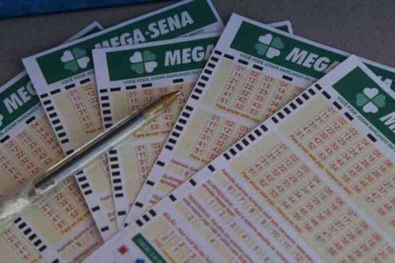 Na imagem h vrios bilhetes de apostas da Mega Sena enfileirados com uma caneta em cima 
