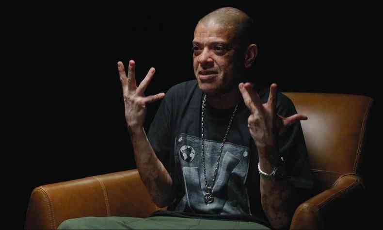 KL Jay gesticula, sentado na poltrona, em cena de documentrio sobre a banda Racionais