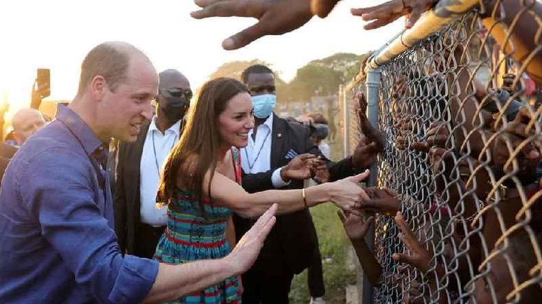 O duque e a duquesa de Cambridge cumprimentam crianças jamaicanas por uma cerca de arame em Trench Town, bairro pobre de Kingston, capital da Jamaica(foto: Reuters) O duque e a duquesa de Cambridge cumprimentam crianças jamaicanas por uma cerca de arame