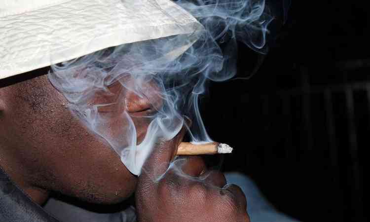 homem de chapu fumando um cigarro de maconha