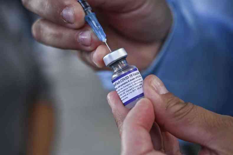 Na imagem h um homem segurando um frasco de vacina e retirando o contedo com uma seringa 