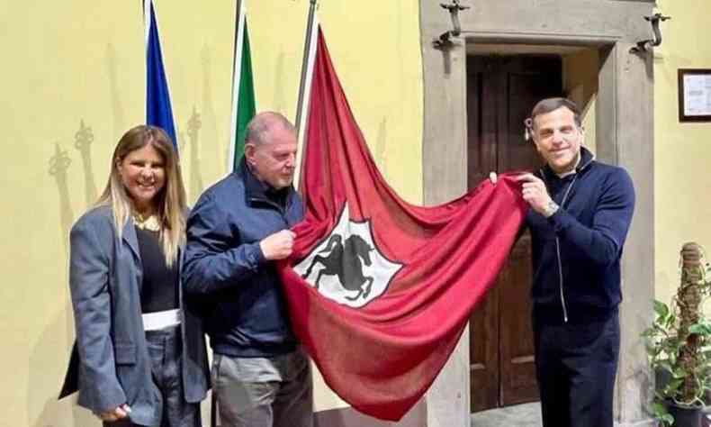 Luciana Wodzik sorri, enquanto, ao lado dela, Anderson e Alexandre Birman seguram bandeira em cerimnia na cidade de Arezzo, na Itlia