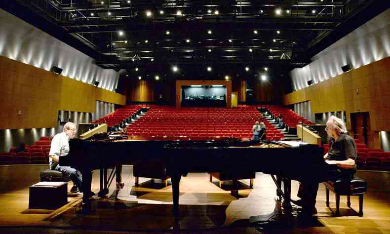 Arthur Moreira Lima e Joo Carlos Martins sentados em seus respectivos pianos ensaiam no palco do teatro do Centro Cultural Unimed-BH Minas
