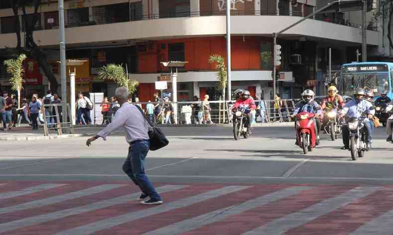 homem de cabelo branco correndo para atravessar avenida