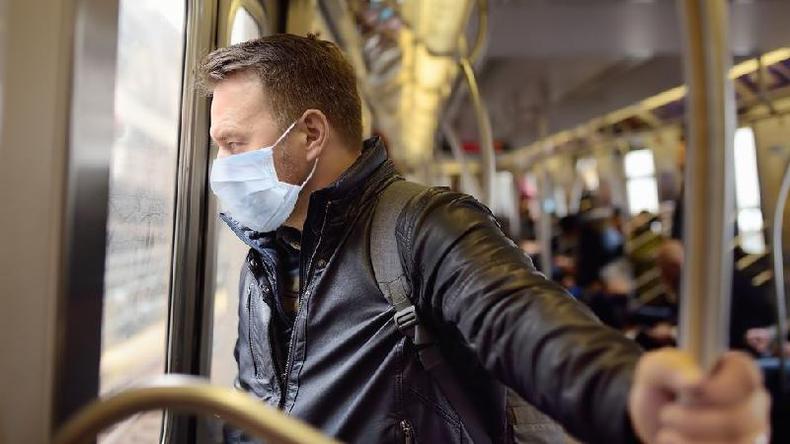 Homem de mscara em p no transporte pblico