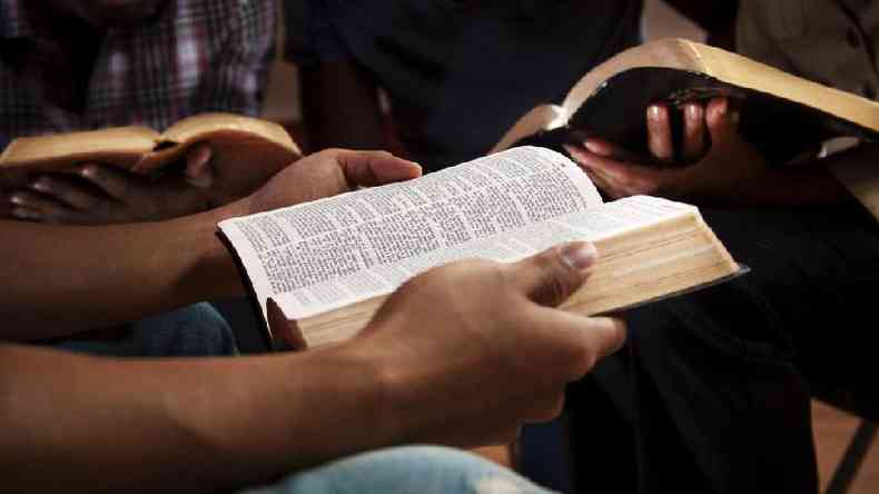 Close nas mos de pessoas segurando biblias em uma roda de conversa