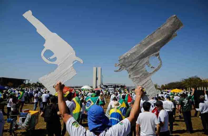 Manifestante segura cartazes em formato de armas, durante protesto pr-Bolsonaro em Braslia em julho