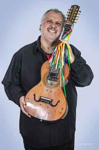 de p, vestido de preto e carregando sua viola, Chico Lobo sorri 
