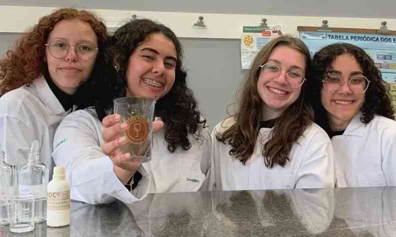Quatro jovens de 16 e 17 anos, com jaleco branco em um laboratrio mostrando o copo desenvolvido para detectar a presena da substancia GHB, mais conhecido como 'Boa noite Cinderela'