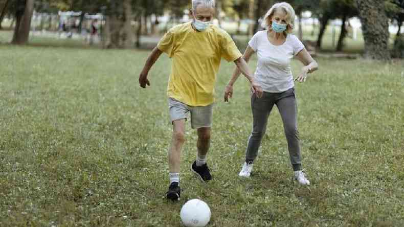 Homem e mulher de mscara jogam futebol