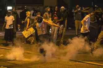 Manifestante chuta bomba de gs lacrimogneo para a polcia em protesto pelo assassinato de jovem negro, em Ferguson, no Missouri (foto: AFP Photo)