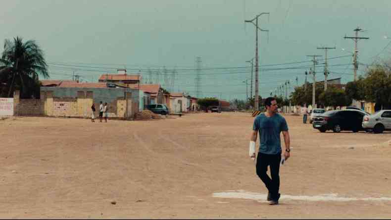 com mo na tipoia e de camisa verde em ambiente aberto, ator Antonio Saboia olha para o lado em cena do filme 'Deserto particular'