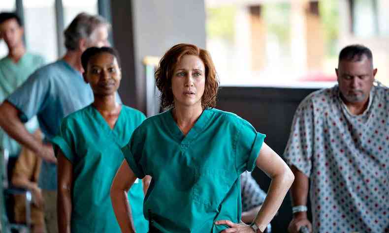 Com uniforme verde de mdica, a atriz Vera Farmiga em frente a atores no papel da equipe do Hospital Memorial em cena da srie Cinco dias no Hospital Memorial