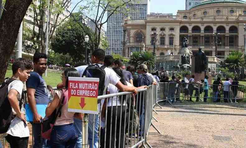 Fila de pessoas onde h uma placa na qual se l 'fila mutiro do emprego'