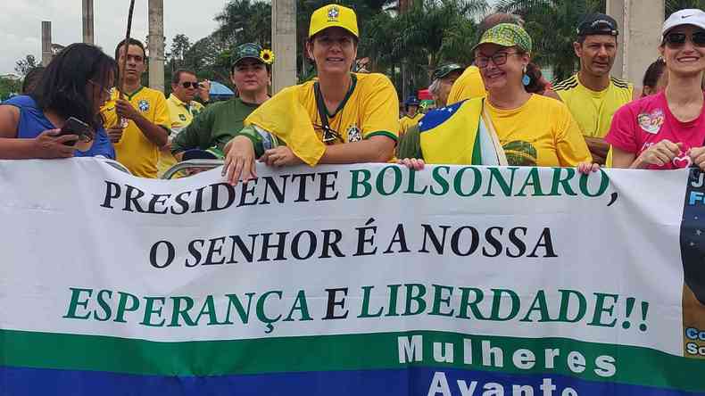 Apoiadoras de Jair Bolsonaro esperam pela chegada da primeira-dama com faixas e blusas do Brasil