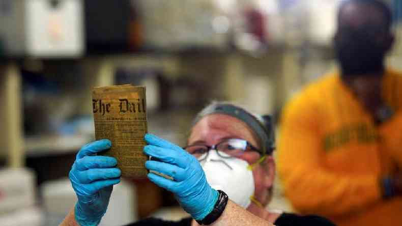 Integrante da equipe de preservação do Departamento de Recursos Históricos da Virgínia mostra mais um item da 'cápsula do tempo'
