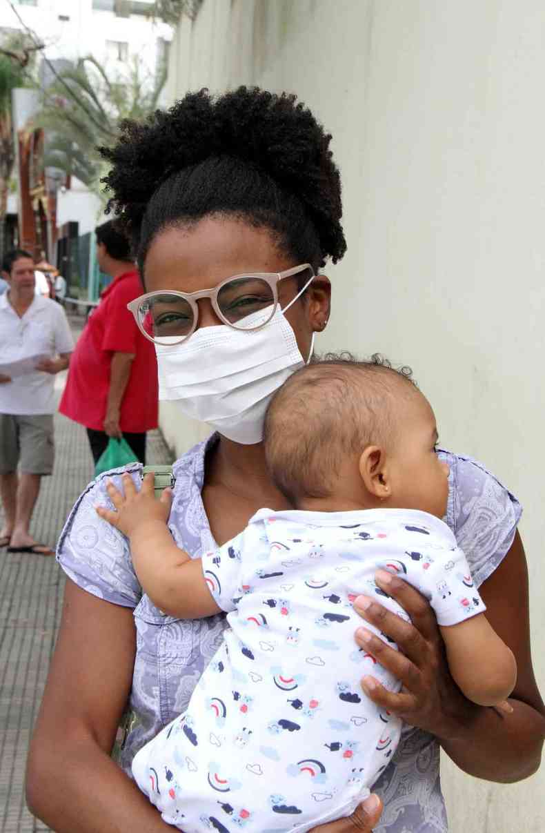 Poliana Cruz, usando uma mscara branca e um culos, segurando a Maya no colo