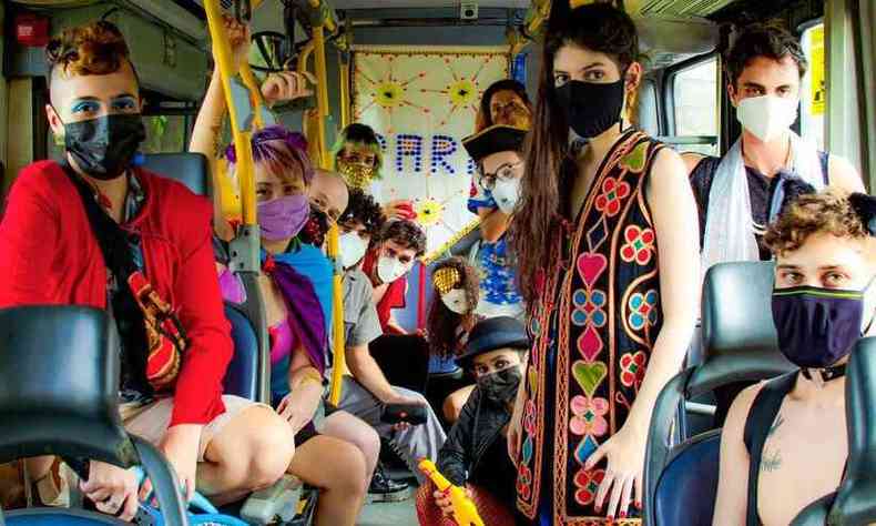 Integrantes do Bloco Pare, formado pela artista Sara No Tem Nome e amigos, esto sentados dentro de um nibus e vestem fantasias de carnaval