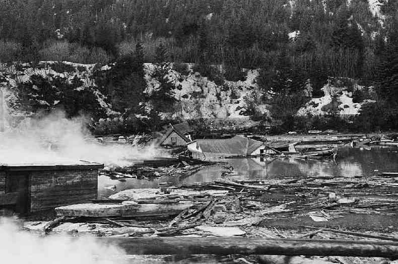 Fumaa de restos de tanques de leo entre runas de casas aps terremoto e maremoto no Alaska