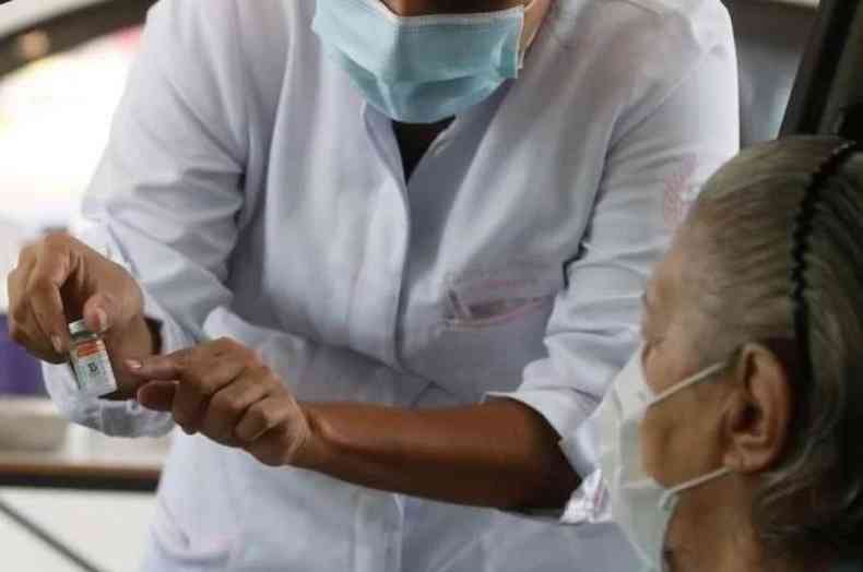 Mulher aplicando vacina em paciente