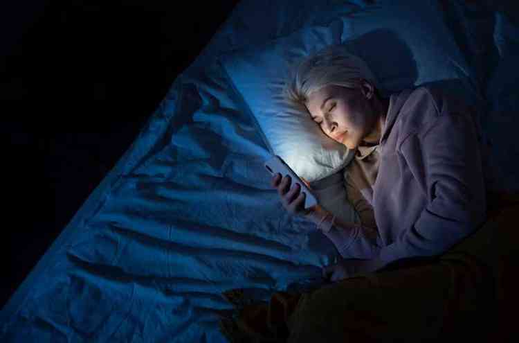 Mulher olhando celular na cama à noite