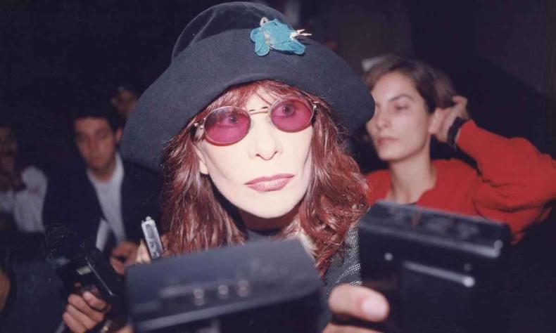 Rita Lee durante entrevista coletiva no Palácio das Artes no início dos anos 1990(foto: Helvécio Carlos/EM/D.A Press) Rita Lee, usando óculos escuros e chapéu, dá entrevista e tem gravadores diante de seu rosto