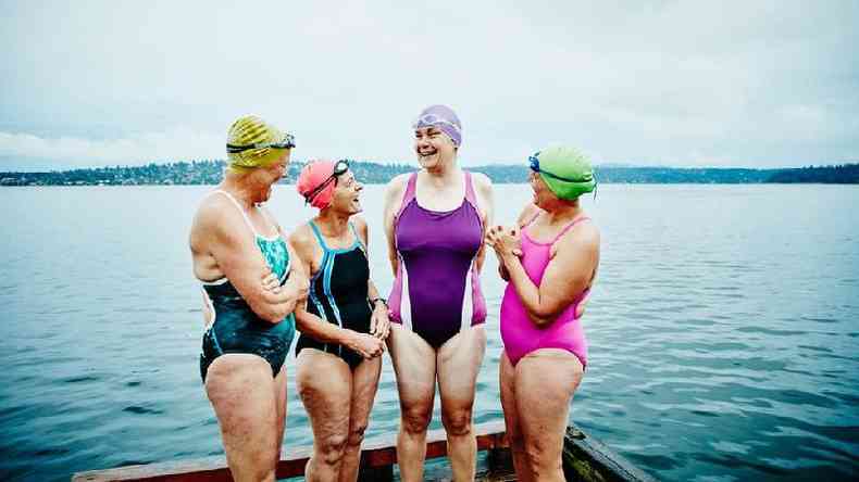 Quatro mulheres de meia-idade sorridentes de mai em frente a um lago