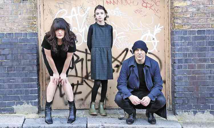 Vestidos de preto em frente a parede pichada, Bruno Verner, Eliete Mejorado e Yoko Afi posam para foto
