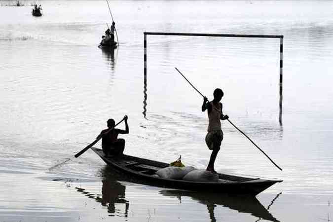 Moradores das reas atingidas pelas enchentes usam canoas para levar comida para as famlias ilhadas(foto: STRDEL / AFP)