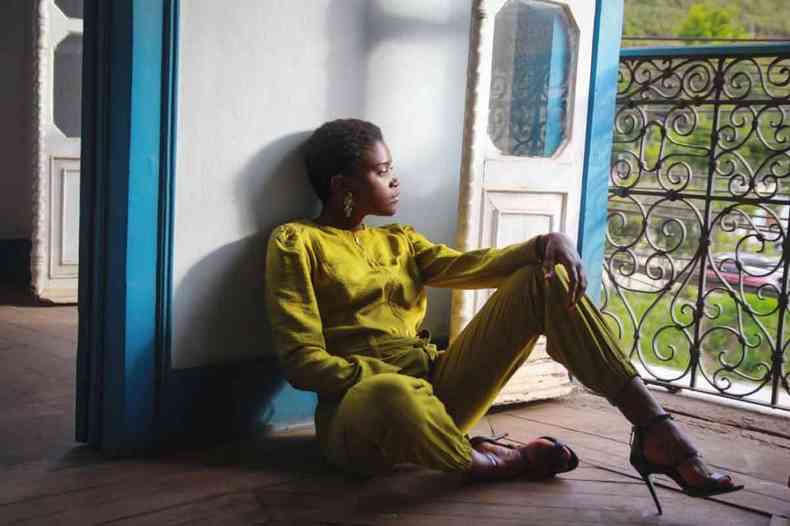 Modelo Samara Assis sentada no chão, olhando pela janela, em ensaio de moda realizado há algum tempo em casarão que desabou em Ouro Preto, na semana passada