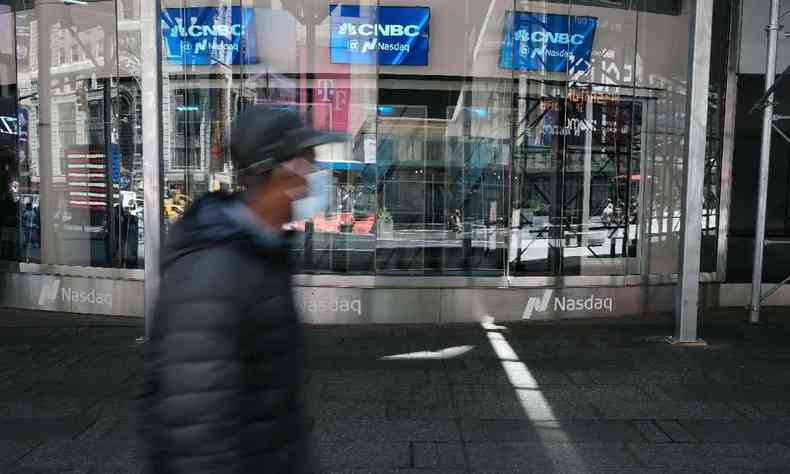 Pessoas caminham pelo site Nasdaq Composite na Times Square, enquanto as aes globais caram na tera-feira,  medida que aumentam as preocupaes de que o aumento da inflao levar os bancos centrais a apertar a poltica monetria em 11 de maio de 2021 na cidade de Nova York