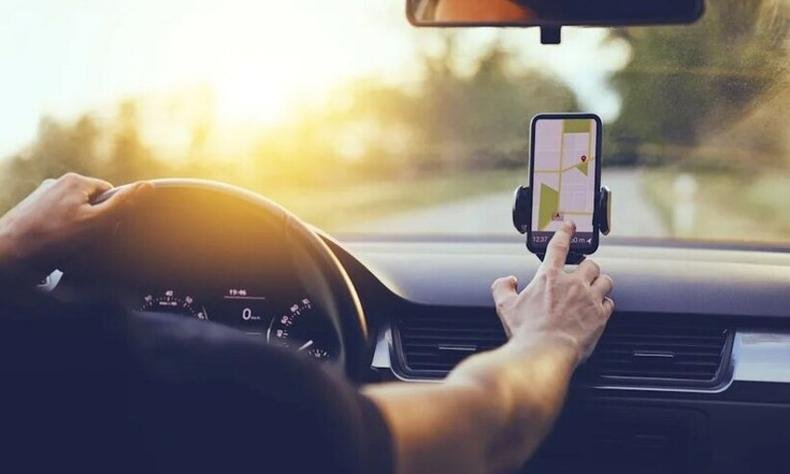 Foto ilustrativa de um motorista olhando aplicativo em um celular
