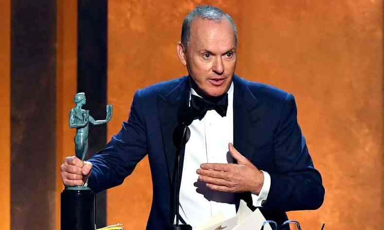 ator Michael Keaton segura o SAG Award com uma das mos e olha para a plateia do teatro em LA