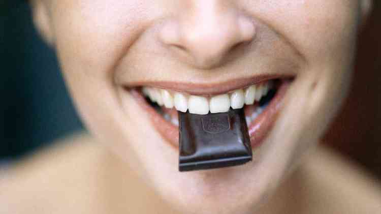 Mulher com pedaço de chocolate na boca