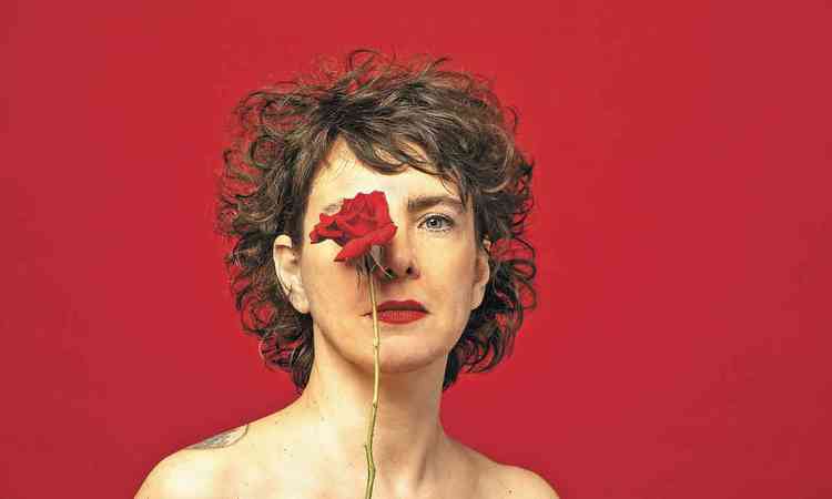 Adriana Calcanhotto cobre um de seus olhos com uma rosa vermelha
