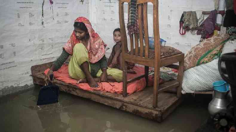 Mulher e menina em cmodo inundado em Chittagong