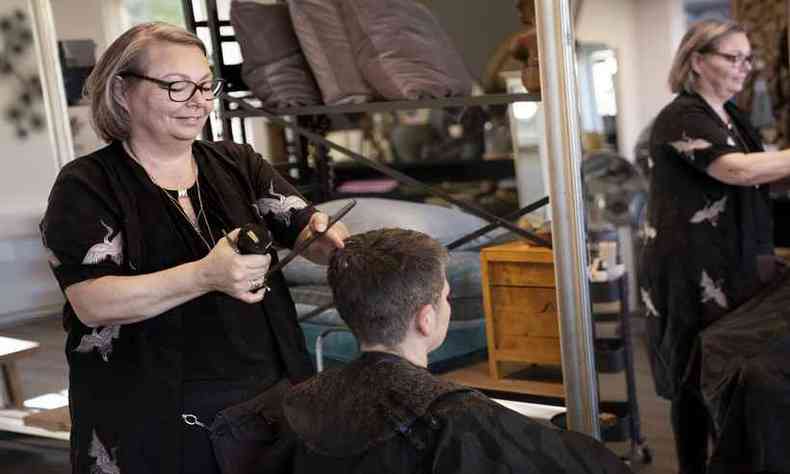 Cabeleireira Christel Lerche cortando o cabelo de um cliente nesta segunda-feira, aps cinco semanas de portas fechadas(foto: Ritzau Scanpix / AFP)