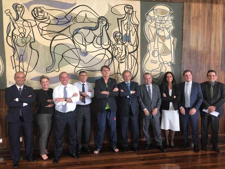 Ex-presidente Jair Bolsonaro no centro de chinelos com ministros em frente a uma tapearia de autoria do artista Di Cavalcanti