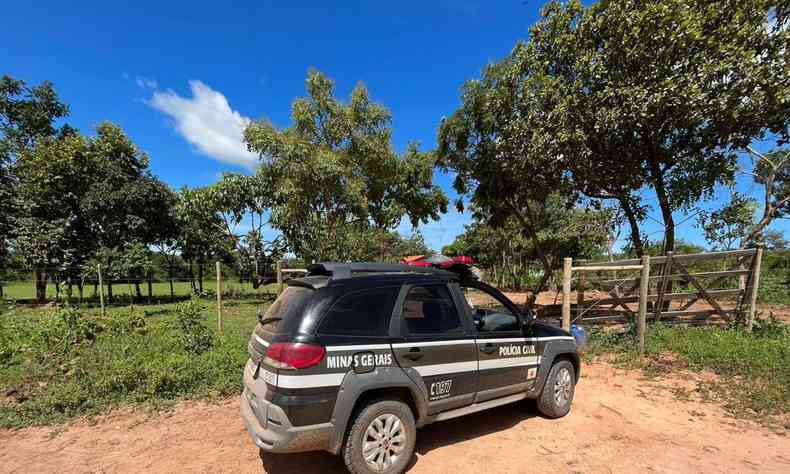 Viatura da Polcia Civil estacionada em rea rural, em cho de terra batida. Carro aparece de perfil, perto de uma cerca de madeira. Ao fundo, h algumas rvores e uma rea gramada. 