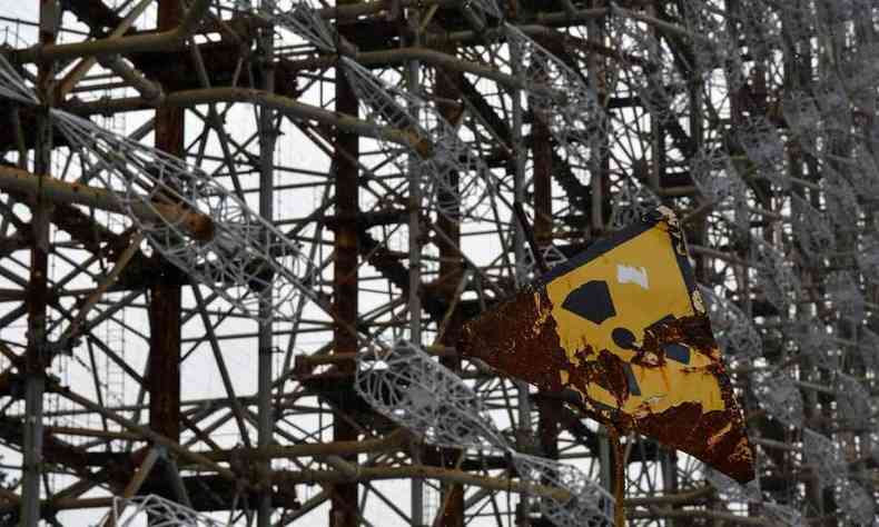 Placa indica perigo de radiao em frente ao radar Duga-1, perto da antiga usina nuclear de Chernobyl (foto: GENYA SAVILOV / AFP)