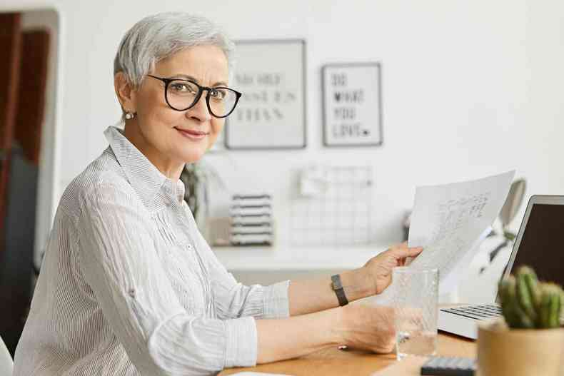 Mulher de idade lendo um documento de aposentadoria
