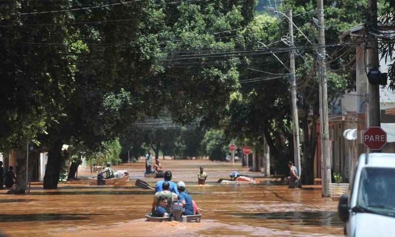 Chuva deixou dezenas desalojados em Governador Valadares, na primeira quinzena de janeiro(foto: Alexandre Guzanshe/EM/D.A Press) Pessoas transitam por barcos em rua tomada pela água em Governador Valadares