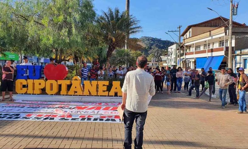 Felipe a frente da placa 'Eu amo Cipotnea', moradores em volta