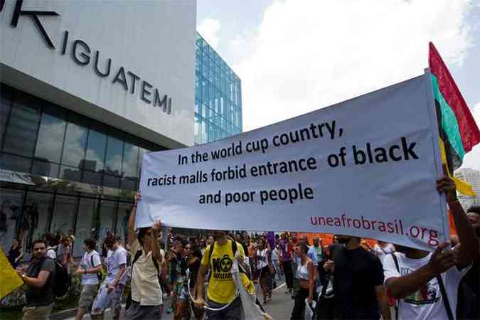 Participantes de movimentos sociais e estudantis protestam do lado de fora do shopping Iguatemi, em SP. A faixa diz: No ano da Copa do Mundo, os shopings racistas probem a entrada de gente pobre e preta(foto: AFP PHOTO/Nelson Almeida )