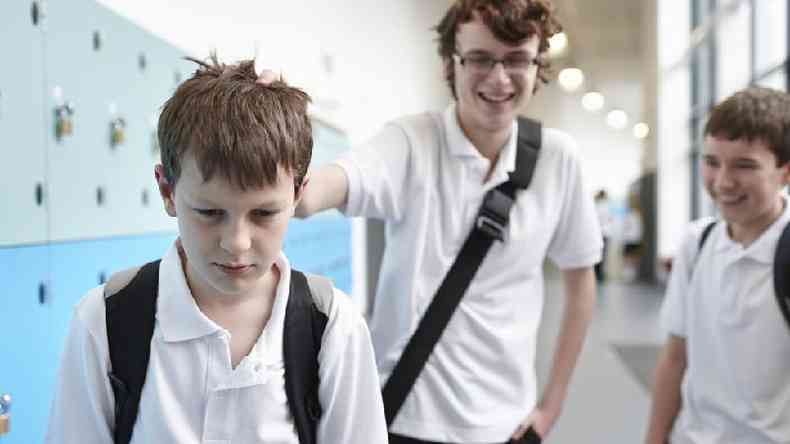 Menino segurando a cabea de colega em vestirio na escola