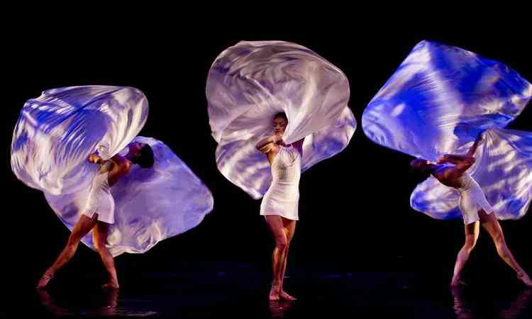 Trs bailarinas do grupo Momix executam coreografia levantando leves tecidos para o alto