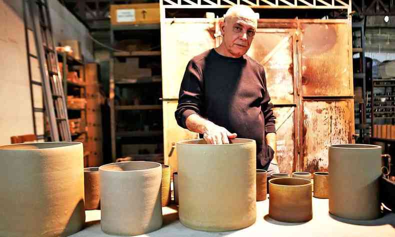 Mximo Soalheiro est em seu ateli, com a mo sobre uma de suas cermicas colocadas sobre a mesa 